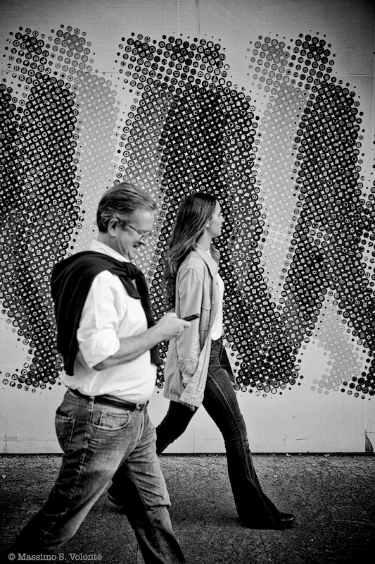 People passing by a billiborad of people passing by, monochrome, fotografo milano